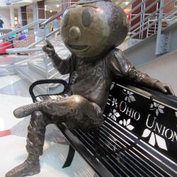 Side view of copper Brutus statue sitting on bench